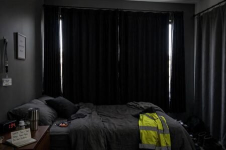 Blackout curtains with side panels blocking daylight in a dark bedroom for shift workers