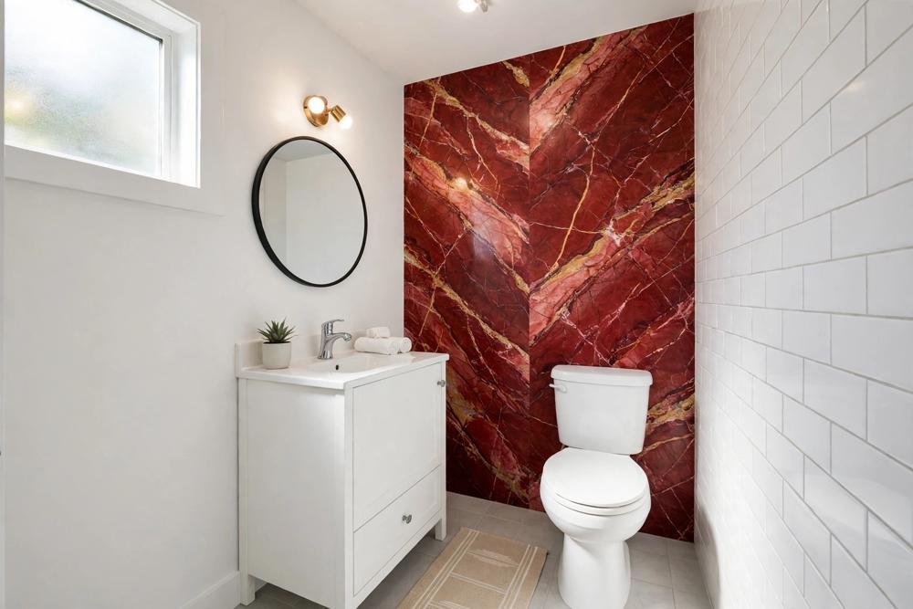 Small bathroom with a red marble accent wall, plain white fixtures and a simple rug